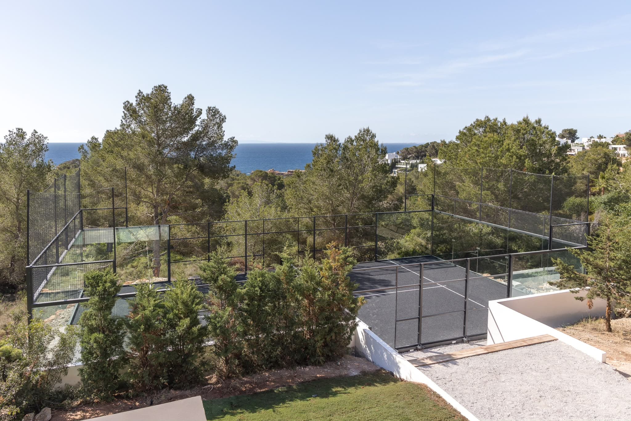 A padel court above the sea, the Mediterranean open behind the back fence