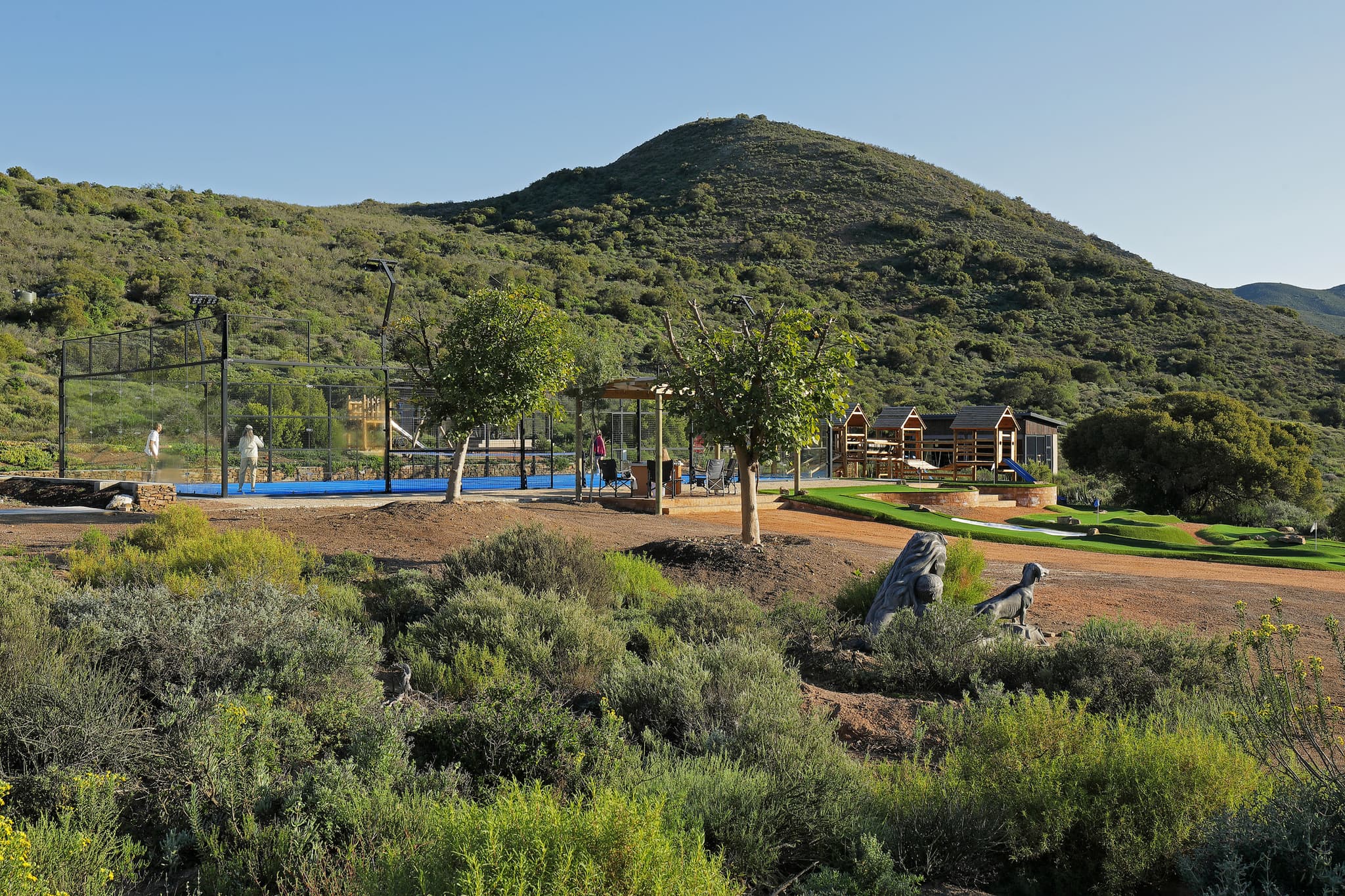 A padel court cut into the hillside, the Karoo behind it