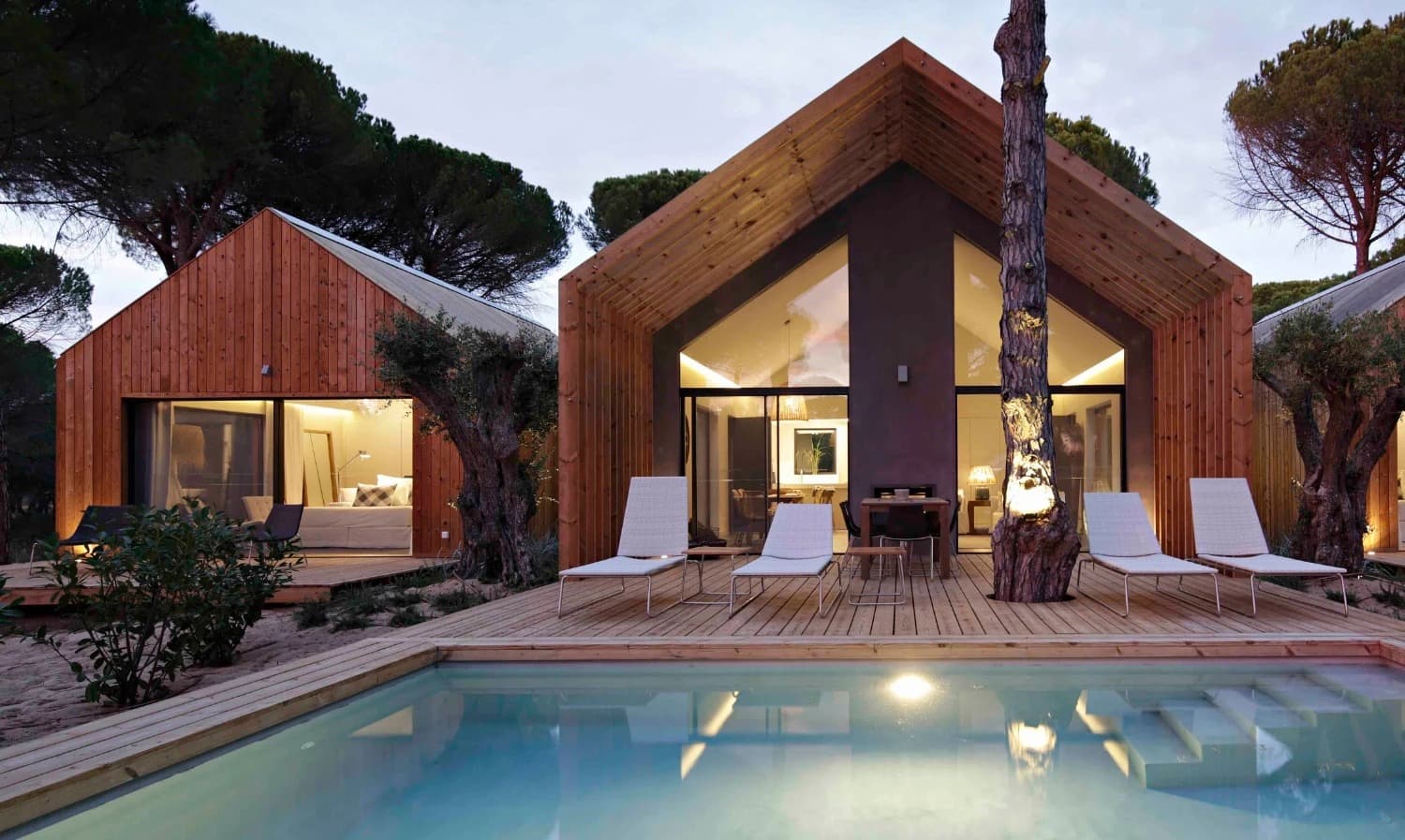 The gabled cabin at dusk, its pool holding the last of the light