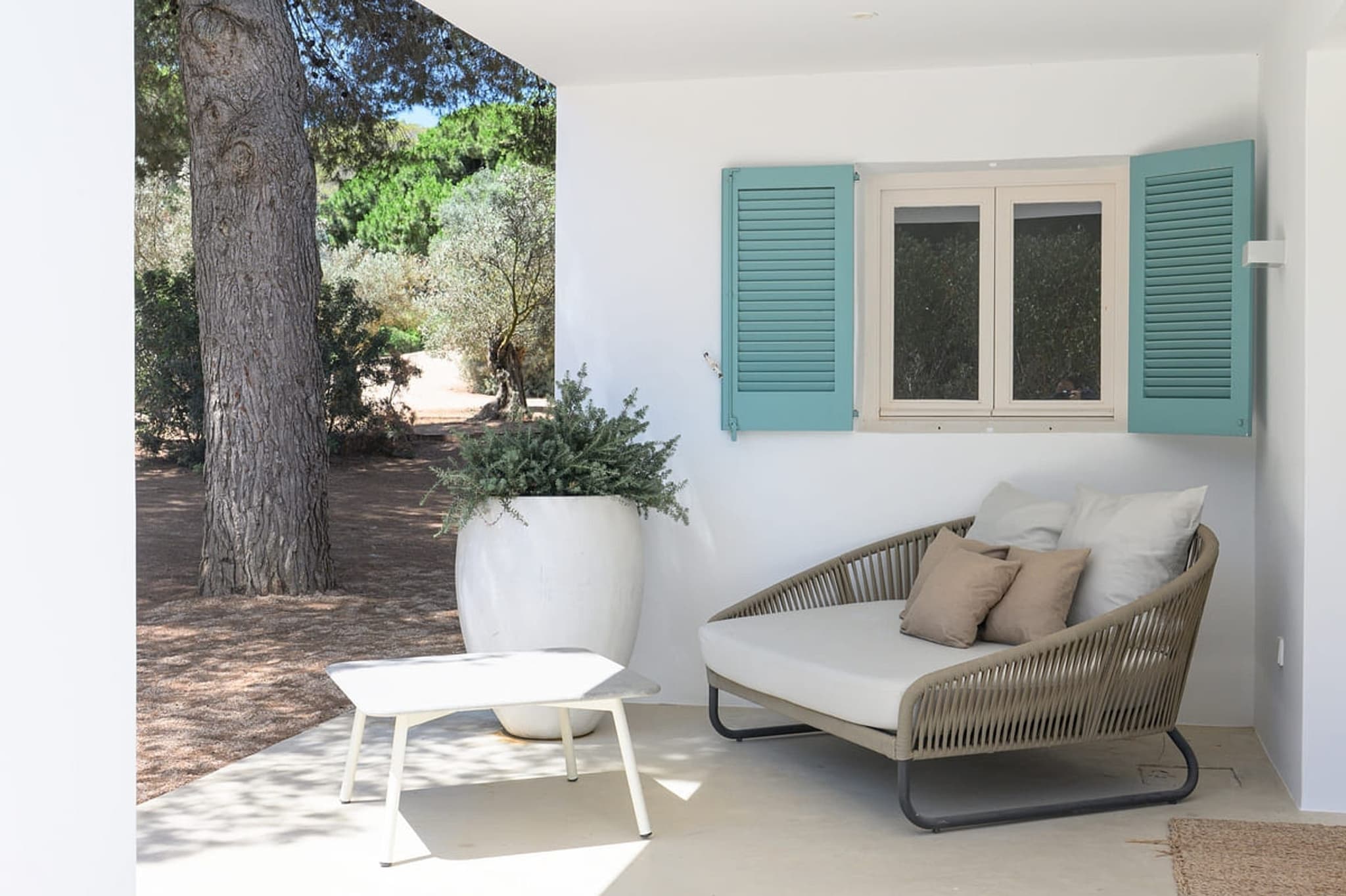 A rattan sofa on the terrace, shutters behind