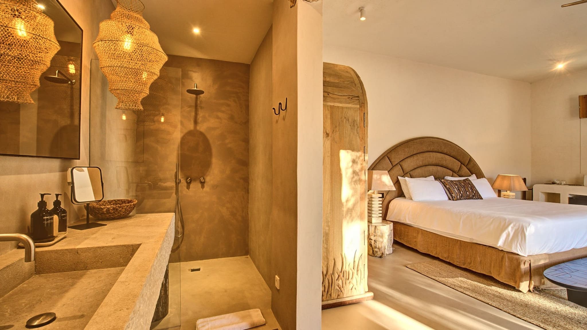 A microcement ensuite off the bedroom, brass lamps lit