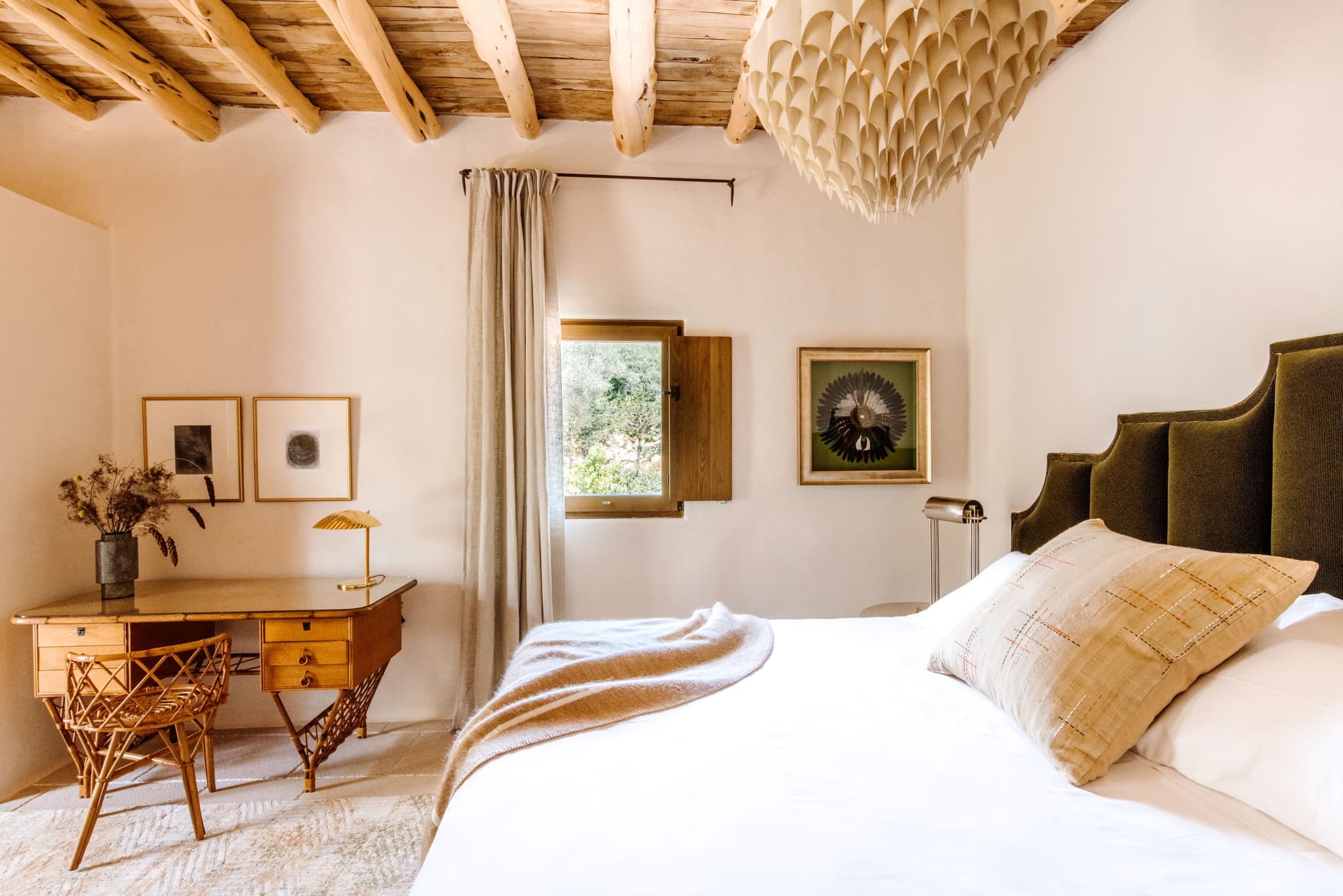An olive headboard, a wood desk under the window