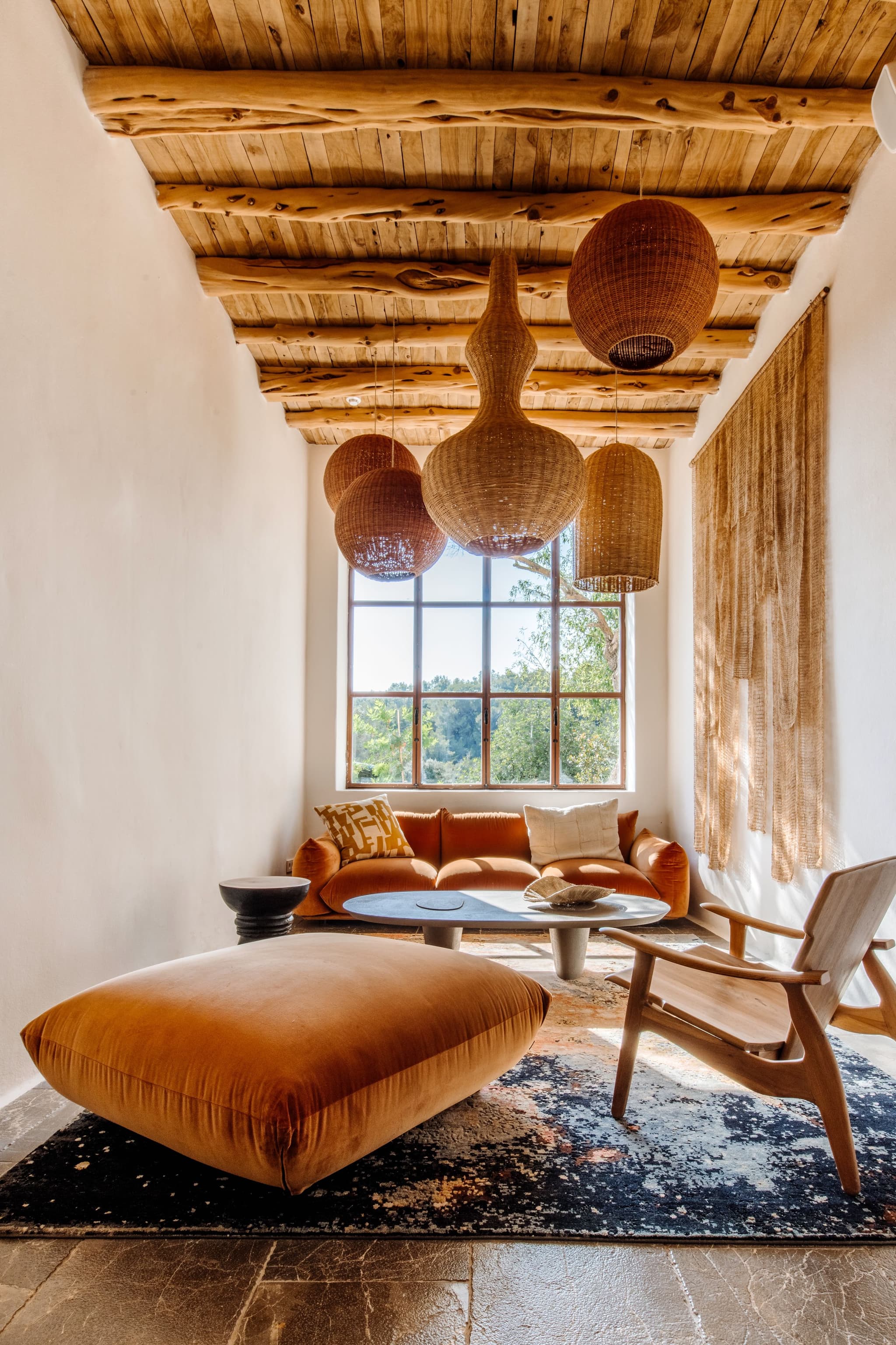 An orange velvet nook under woven pendants