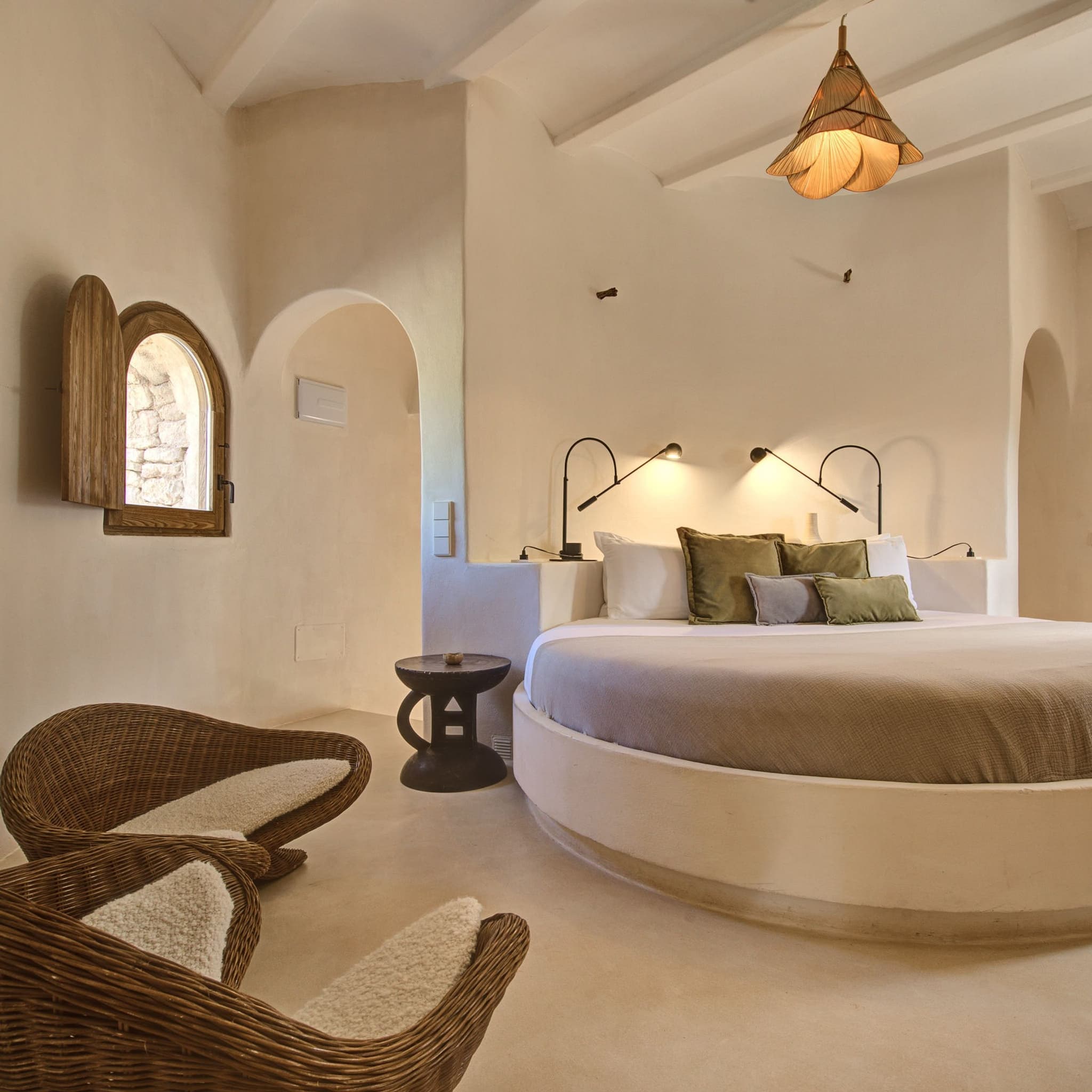 A round bed in the plaster suite, wicker chairs beside it