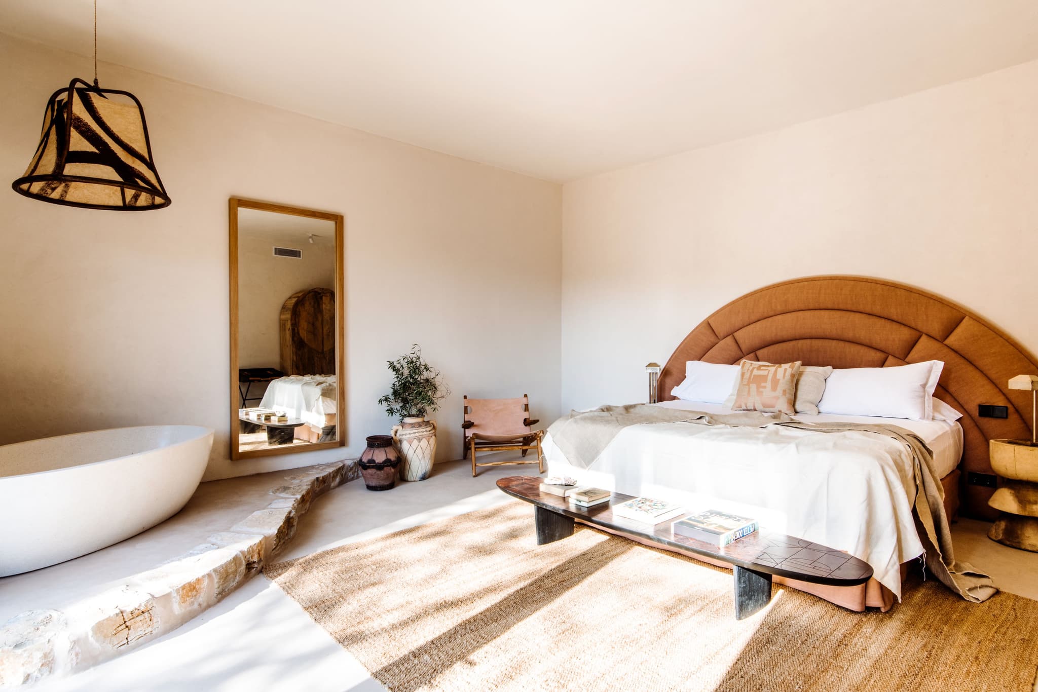 A freestanding bath at the foot of the terracotta headboard