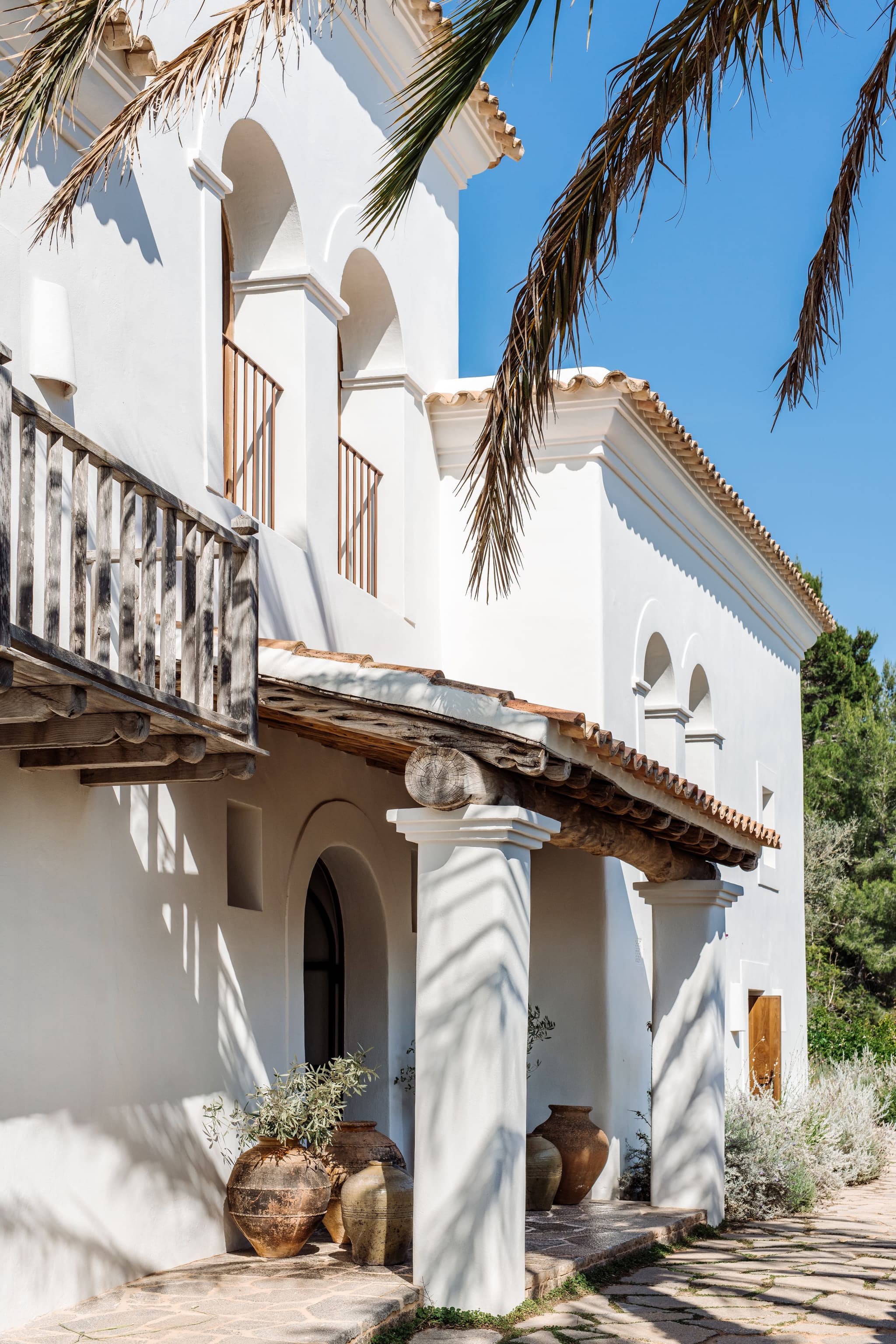 The whitewashed facade, a palm beside the balcony