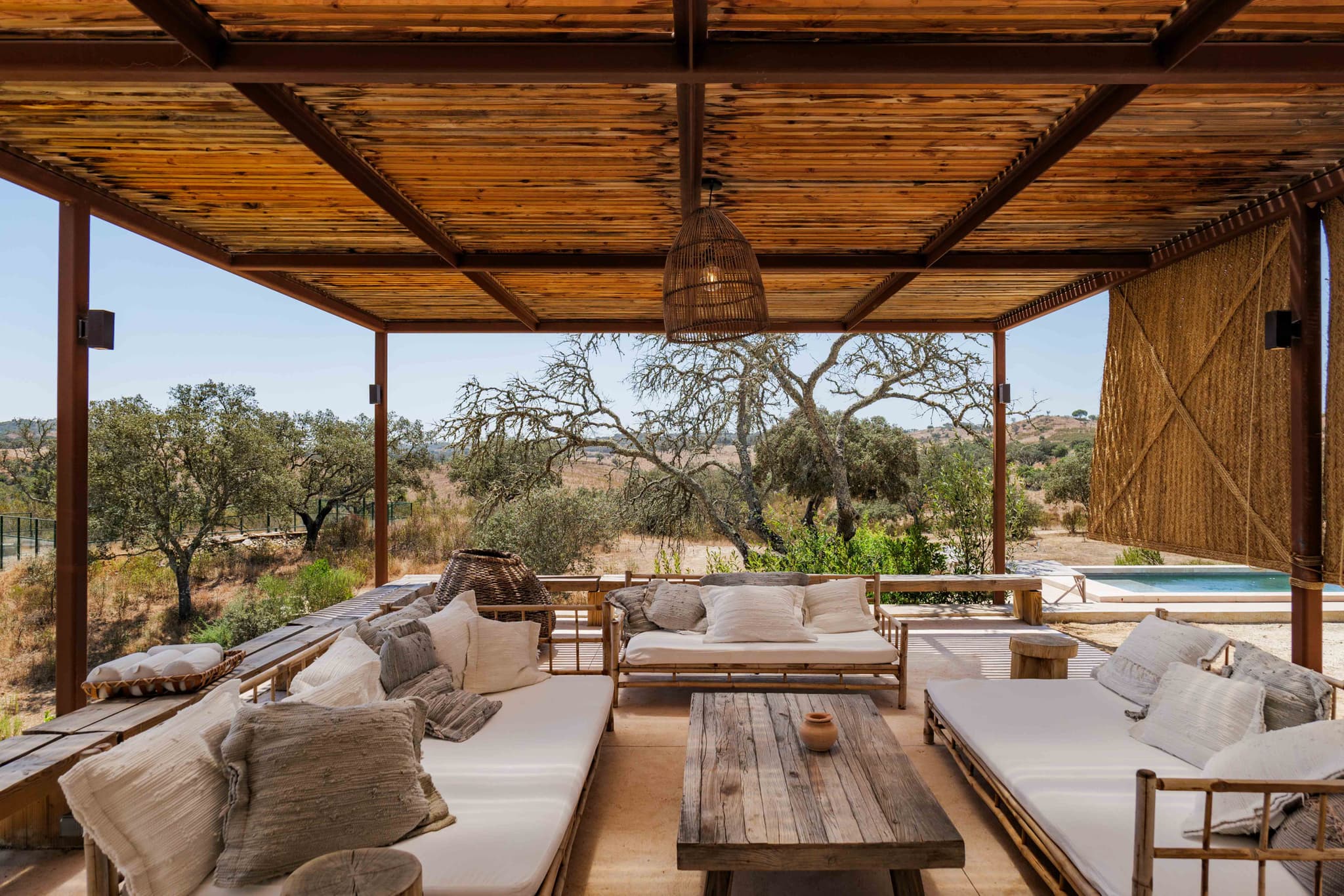 Sofas on the shaded terrace, with the pool in view